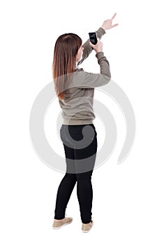 Back view of pointing young beautiful woman and using a mobile