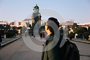 Back view portrait of Asian male tourist backpacker carrying a bag in Maria Theresa Monument in Vienna, Austria