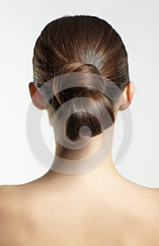 Back view portrait of beautiful young dark brunette woman on gray background