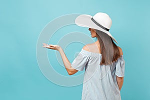 Back view portrait of elegant fashion young woman in white summer large wide brim sun hat, dress put hands on head