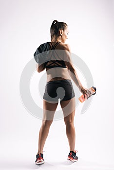 Back view portrait of muscular sexy young woman holding bottled water in hand