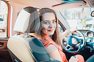 Back view Portrait of smiling business lady, caucasian young woman driver looking at camera and smiling over her shoulder while