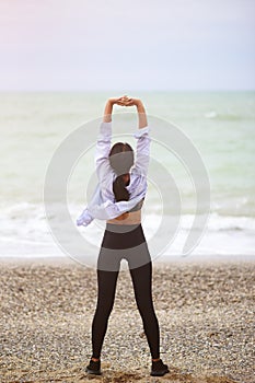 Back view portrait of woman stretching her arms up.