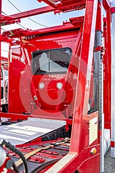 Back view of red big rig semi truck tractor with hydraulic modular two level semi trailer standing on the warehouse parking lot at