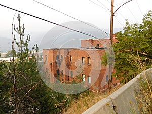 The back view of a red brick building in Keoogg, Idaho. Fog almost obscures the adjacent mountains in the distance