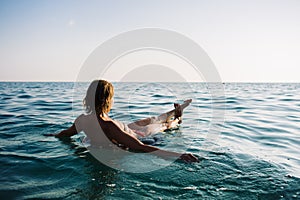 Back view of relaxing woman floating on inflatable ring