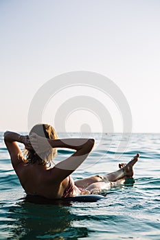 Back view of relaxing woman floating on inflatable ring