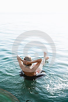 Back view of relaxing woman floating on inflatable ring