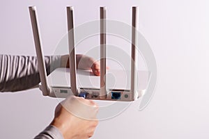 The back view of router showing the lan internet port, and the hand is plugging in the land cable on a white router