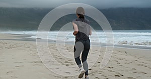 back view Running female runner jogging during outdoor workout on beach., fit