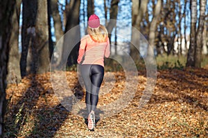 Back view of running girl in fall park in morning