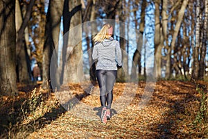 Back view of running girl in fall park in morning