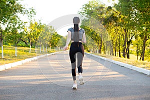 Back view on running sporty woman in the park on road.