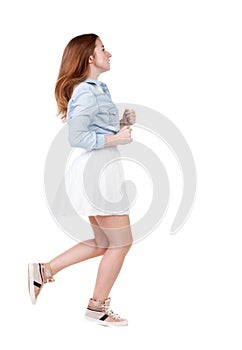 Back view of running woman. beautiful redhead girl in motion.