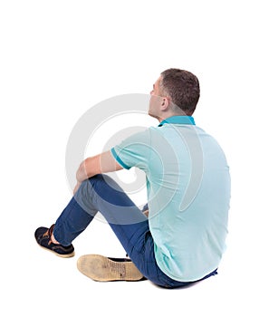 Back view of seated handsome man in polo looking up.