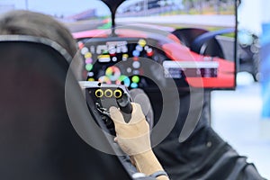 Back view and selective focus right hands of young man gamer who enjoying with racing game via gaming wheel controller