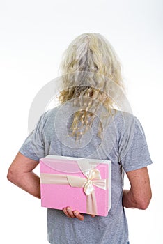 Back view of senior bearded man hiding gift box behind back read
