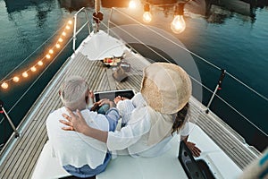 Back view of senior couple having holidays on sail boat - 60`s trendy people enjoying a romantic vacation  - Travel, elderly photo