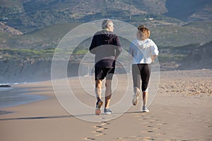 Back view of senior couple training on sea beach