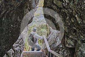 Senior male hiker with backpack, admiring landscape among kissing rocks. Nature park Deer streams