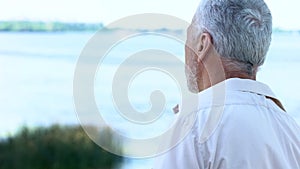 Back view of senior man looking at river and beautiful landscape, tourism