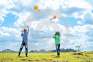 Back view shot of teenager kids flying kite on top of mountain - concept of weekend holidays, relaxation and playful