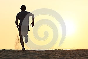 Back view silhouette of a runner man running on the beach