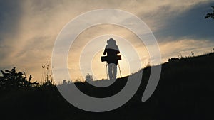 Back view silhouette of walking man with backpack on the mountain