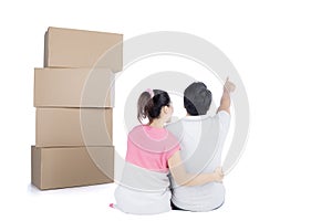 Back view of sitting cute couple with stack of cardboard boxes