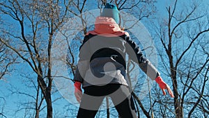 Back view of slim fitness woman working out outdoors in sunny winter