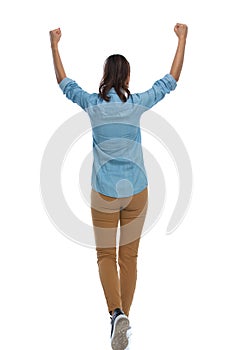 Back view of smart casual woman celebrating and walking