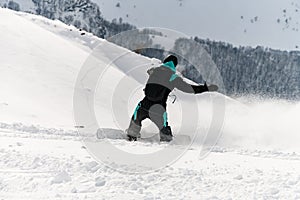 back view of snowboarder riding freeride on powder snow down the slope