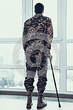 Back view of Soldier Leaning on Crutch By Window