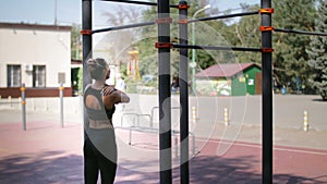 Back view of a sporty fit woman has a shoulder ache. The woman pulled herself up on the bar and was injured by the