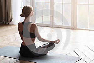 Back view of sporty girl meditating in yoga studio