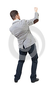 Back view of standing man pulling a rope from the top or cling t