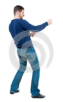 Back view of standing man pulling a rope from the top or cling t photo