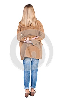 Back view of standing young beautiful blonde woman in brown clo