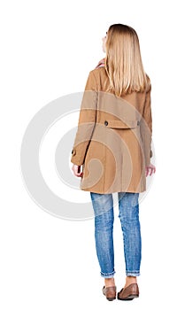 Back view of standing young beautiful blonde woman in brown clo