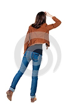 Back view of standing young beautiful brunette woman in brown j