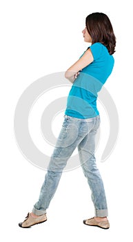 Back view of standing young beautiful brunette woman in jeans.