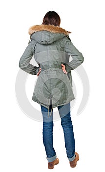 Back view of standing young beautiful brunette woman in park