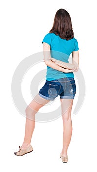 Back view of standing young beautiful brunette woman in shorts.