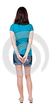 Back view of standing young beautiful brunette woman in shorts.