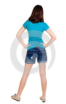 Back view of standing young beautiful brunette woman in shorts.