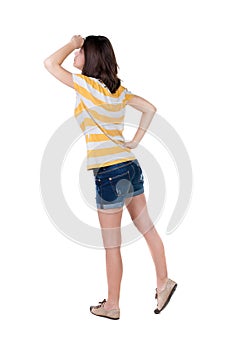 Back view of standing young beautiful brunette woman in yellow