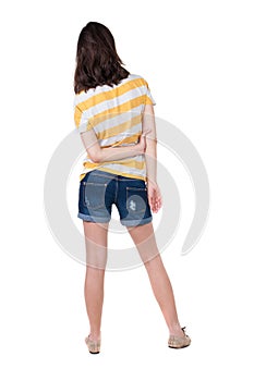 Back view of standing young beautiful brunette woman in yellow