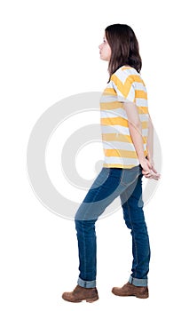 Back view of standing young beautiful brunette woman in yellow