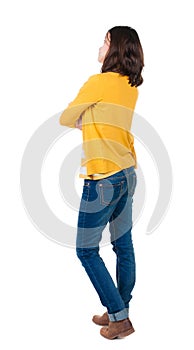 Back view of standing young beautiful brunette woman in yellow