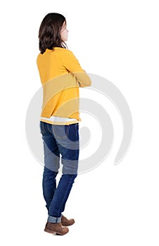 Back view of standing young beautiful brunette woman in yellow